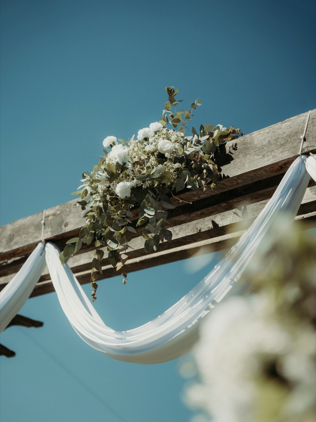 A ceremony arch dressed with greenery and drapery