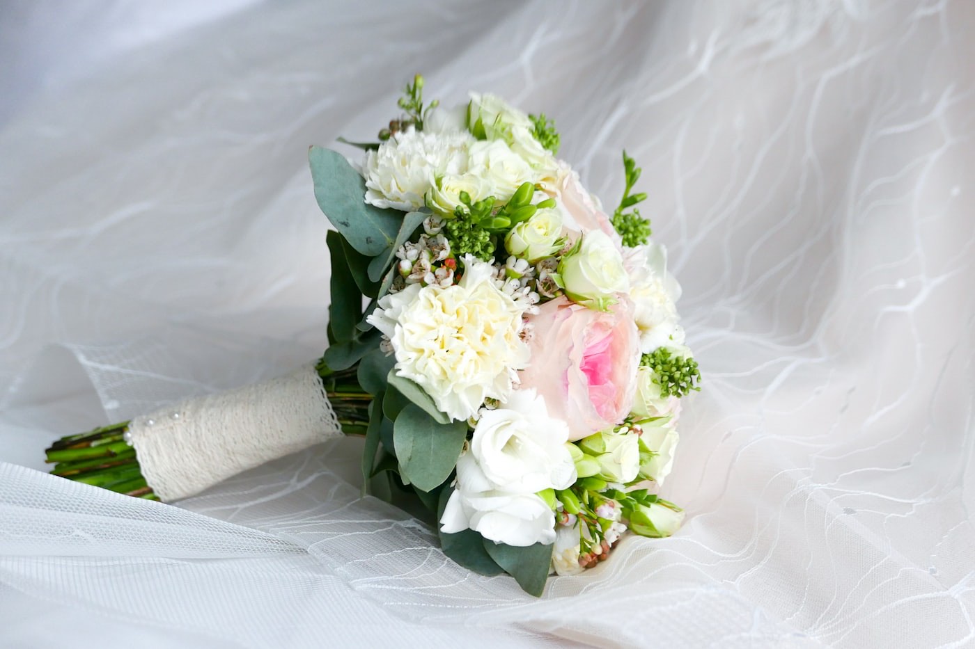 A hand-tied bouquet of blush and ivory roses with eucalyptus